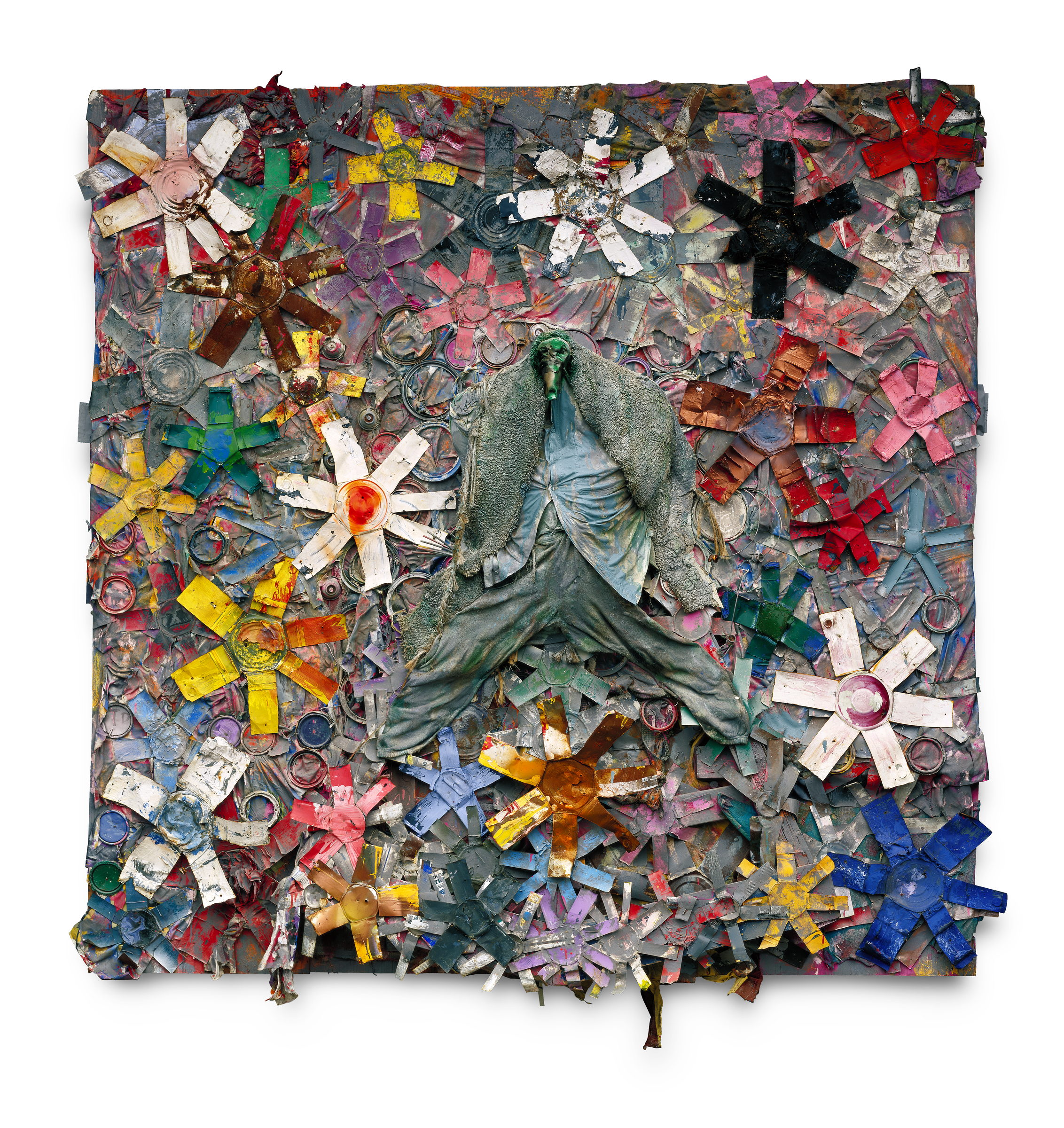 A square wall relief packed edge to edge with six-pointed starbursts cut from flattened paint cans in white, yellow, red, pink, blue and black, their lids still attached at the centres. At the middle, arms and legs flung wide across the stars, a life-size figure made of stiffened work clothes -- jacket, shirt and trousers -- with a green-grey face.